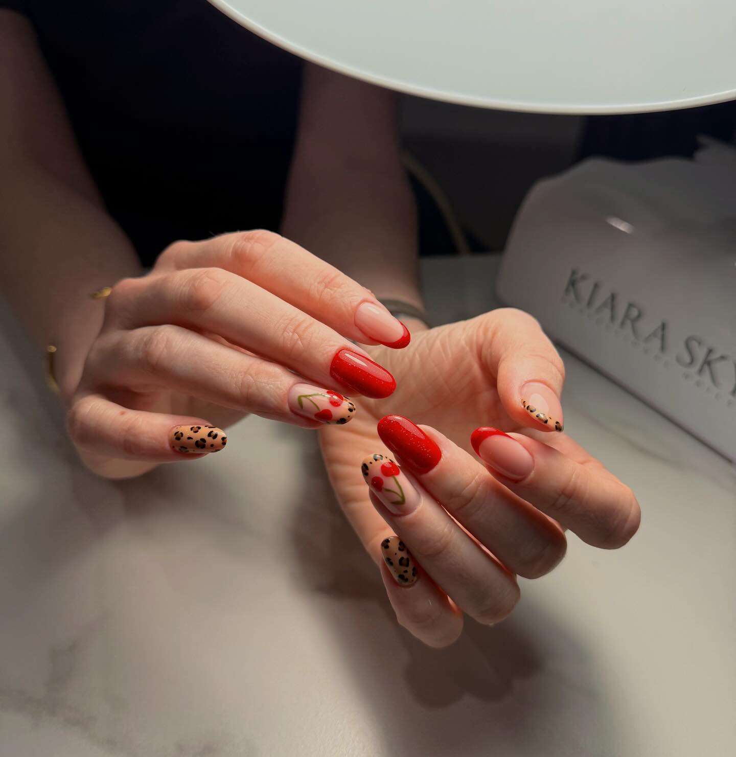 Glossy red nails with cherry and leopard accents